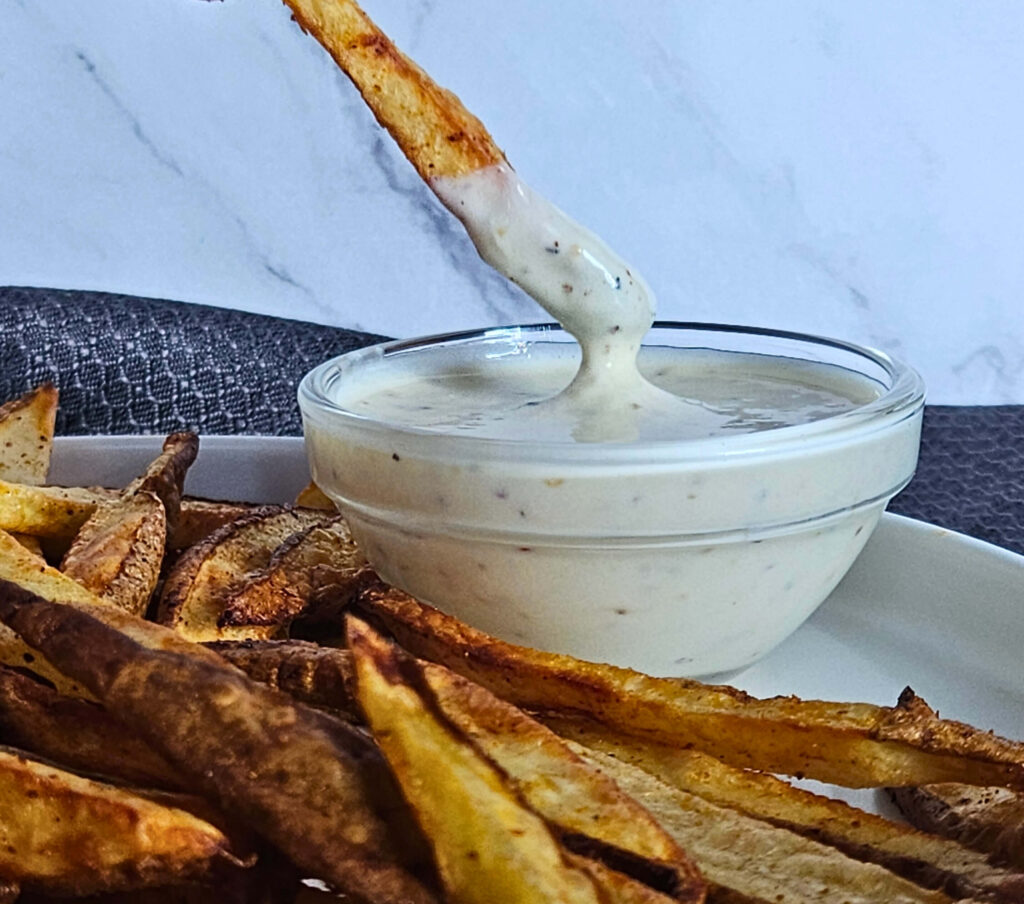 Garlic Aoli 10 Image of French fry being dipping in creamy garlic aioli.