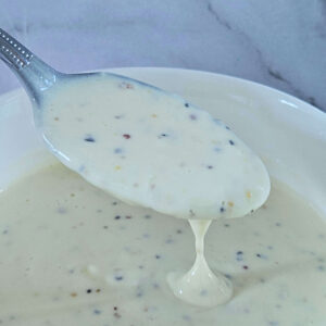 Image of creamy lemon garlic aioli being scooped onto a spoon.