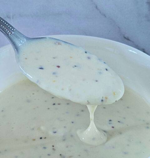 Image of creamy lemon garlic aioli being scooped onto a spoon.