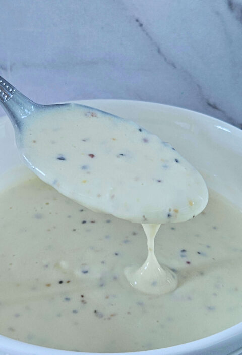 Image of creamy lemon garlic aioli being scooped onto a spoon.