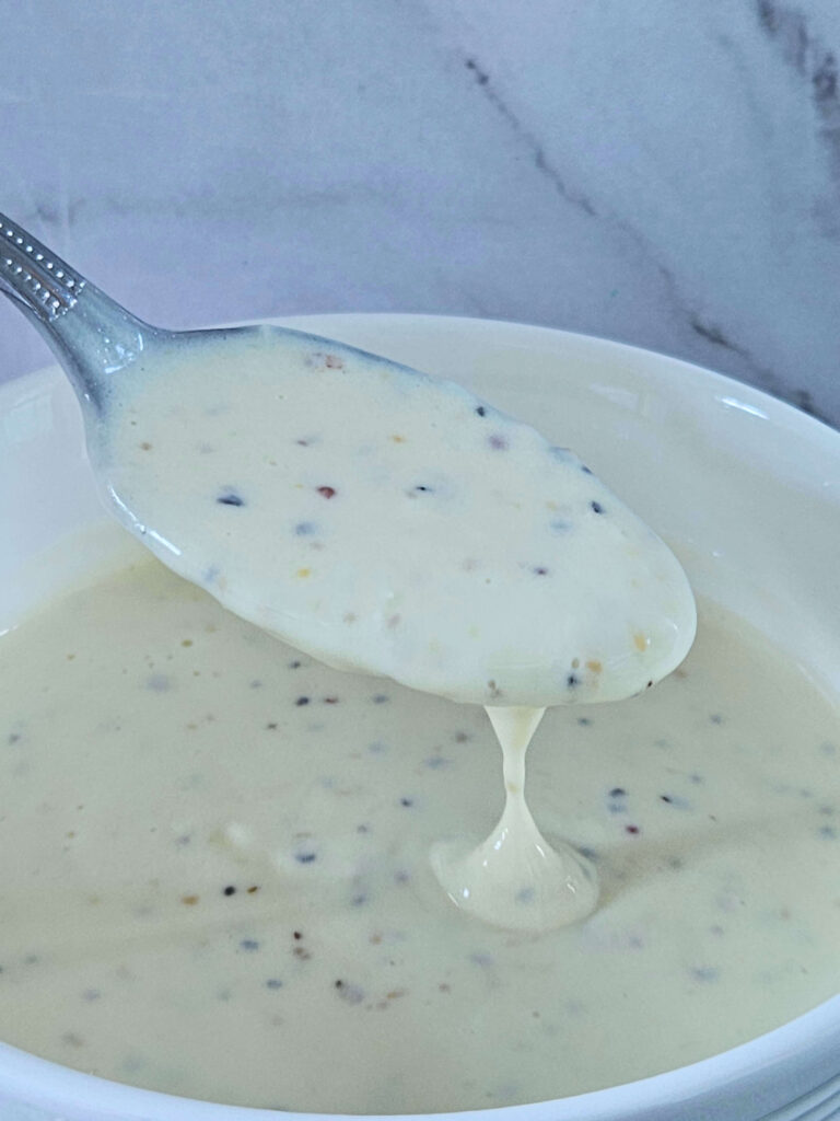 Garlic Aoli 7 Image of creamy lemon garlic aioli being scooped onto a spoon.