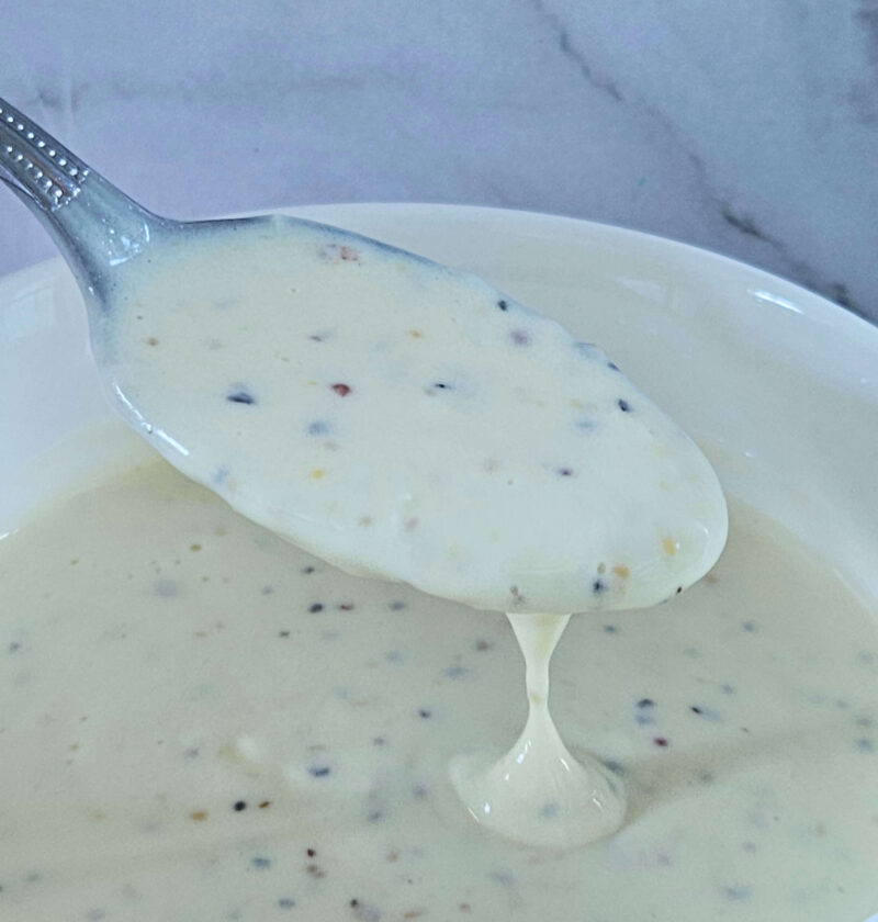 Image of creamy lemon garlic aioli being scooped onto a spoon.