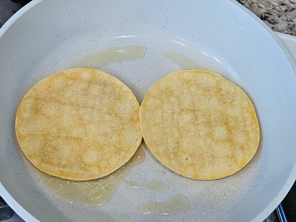 Image of ground chicken smashed dumpling tacos  being seared in a skillet. 