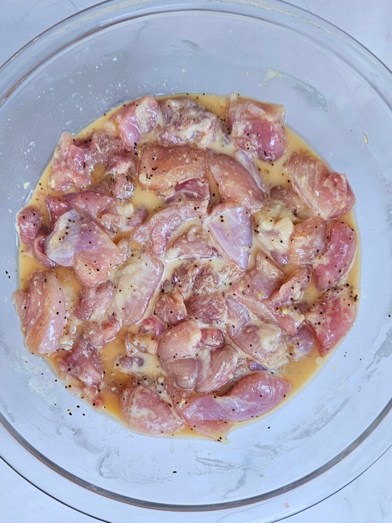 Chicken marinating in a bowl.