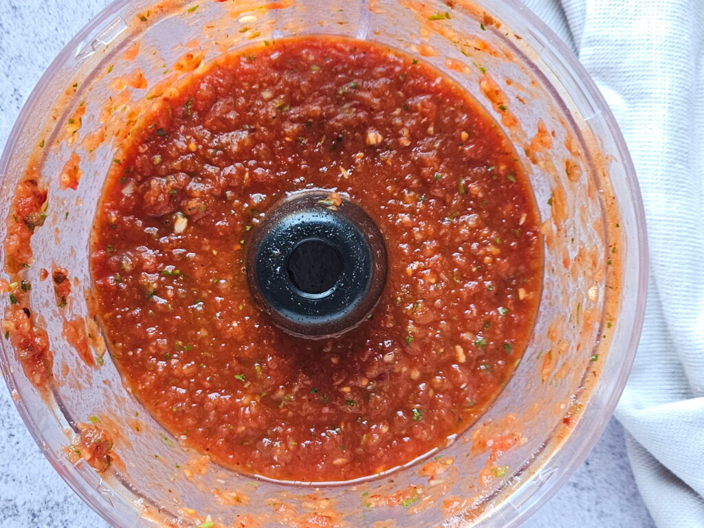 Chipotle Tomato Salsa Prep 2 Image of chipotle tomato salsa in the food processor after being blended.